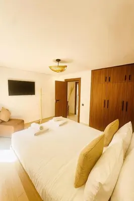 a large white bed in a room with a couch at Duplex 3 chambres - Piscine & Gym à 5 min du Carre Eden - Marrakech Center in Oulad Akkou