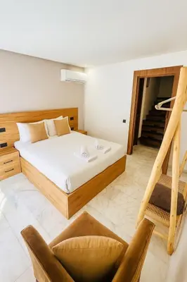 a bedroom with a bed and a staircase and chairs at Duplex 3 chambres - Piscine & Gym à 5 min du Carre Eden - Marrakech Center in Oulad Akkou