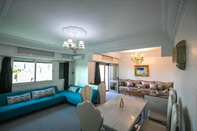 a living room with a table and a blue couch at Luxury Apartment in Fes New City Prime Location in Fès