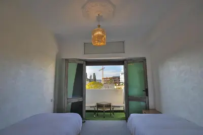 a room with two beds and a window and a chandelier at Luxury Apartment in Fes New City Prime Location in Fès