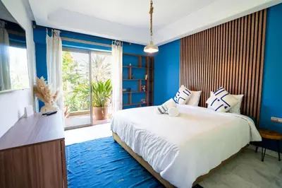 a bedroom with a large bed with blue walls and a window at Appartement de Luxe à Majorelle in Oulad Akkou