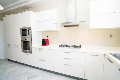 a white kitchen with white cabinets and a red appliance at Appartement de Luxe à Majorelle in Oulad Akkou