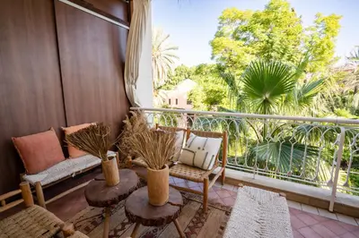 a balcony with a couch and chairs and a large window at Appartement de Luxe à Majorelle in Oulad Akkou