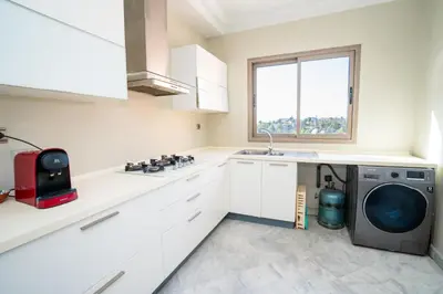 a white kitchen with a washing machine in it at Appartement de Luxe à Majorelle in Oulad Akkou