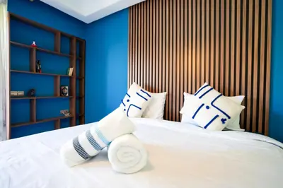 a bedroom with blue walls and a white bed with pillows at Appartement de Luxe à Majorelle in Oulad Akkou