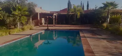 a pool in front of a house with palm trees at Villa Sidi Abdellah Ghiat in Chrabli
