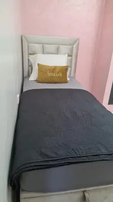 a bed with a black comforter and a yellow pillow at Appartement Fes in Fès