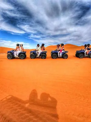 a group of people riding atvs in the desert at Merzouga tarwla camp in Merzouga
