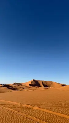 a sand dune in the middle of a desert at Merzouga tarwla camp in Merzouga