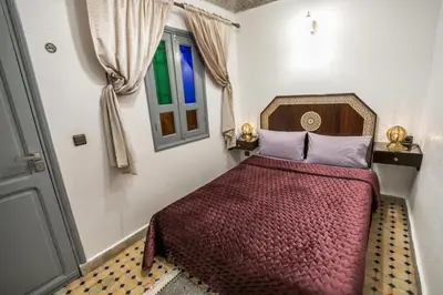 a bedroom with a bed with a red comforter and a window at Riad haje skilf in Fès