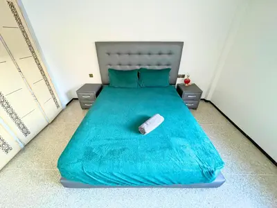 a bed with a blue comforter with a book on it at 3Bed-Room City Centre Apartment - 3 min to Train Station in Fès