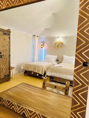 a room with two beds and a mirror at Merzouga Explore Desert Camp in Merzouga
