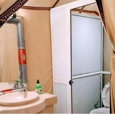 a bathroom with a sink and a glass shower door at Merzouga Explore Desert Camp in Merzouga