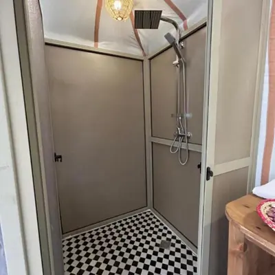 a shower with a door and a checkered floor at Merzouga Explore Desert Camp in Merzouga