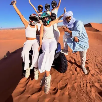 a group of people jumping in the desert at Merzouga Explore Desert Camp in Merzouga