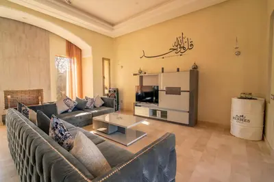 a living room with a couch and a tv at Villa Yasmine Sun, Relaxation & Private Pool in Douar bel Rhanodour