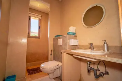 a bathroom with a toilet and a sink and a mirror at Villa Yasmine Sun, Relaxation & Private Pool in Douar bel Rhanodour