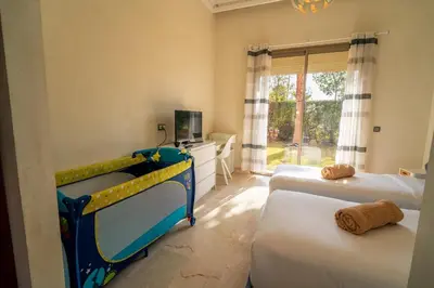 a bedroom with two beds and a tv and a window at Villa Yasmine Sun, Relaxation & Private Pool in Douar bel Rhanodour