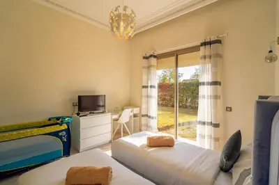 a bedroom with two beds and a tv and a window at Villa Yasmine Sun, Relaxation & Private Pool in Douar bel Rhanodour