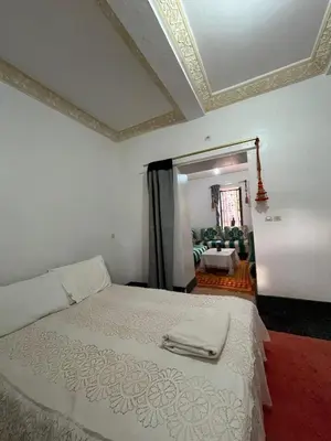 a bedroom with a white bed and a living room at Palmas Magramane Ogandou in Skoura
