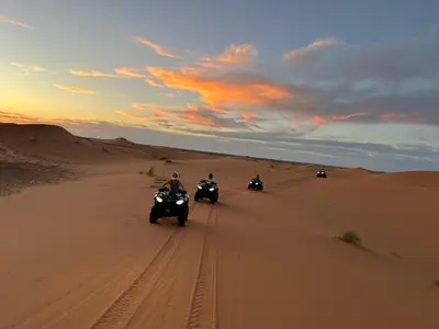 a group of people riding motorcycles in the desert at Merzouga Luxury Desert Camp in Merzouga