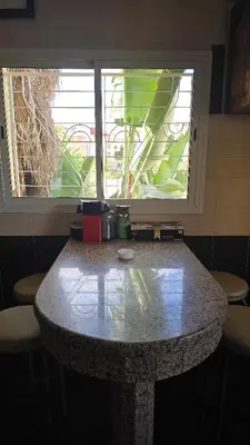 a table in a room with two windows at Meknès Cozy House by Yas in Meknès