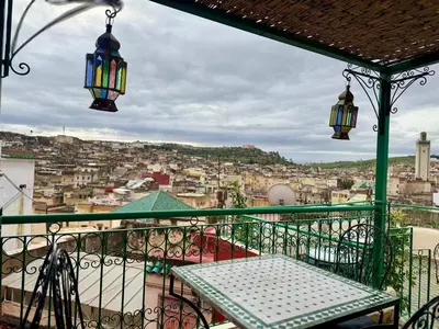 a balcony with a table and lights on a city at Dar Karaouyine Panoramic in Fès