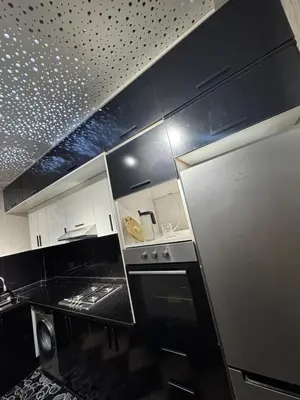 a kitchen with black counters and a stainless steel refrigerator at Appartement confortable près du centre Meknes in Meknès