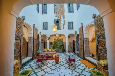 a living room with a chandelier and a table and chairs at Riad Chams Fes in Fès