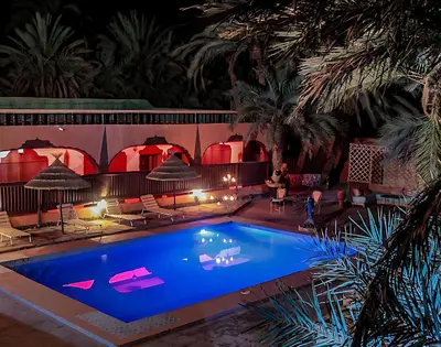 a swimming pool in a resort at night at Maison d'hôtes Ambelar in Erfoud