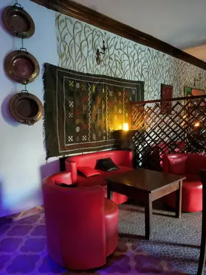 a living room with red chairs and a table at Maison d'hôtes Ambelar in Erfoud