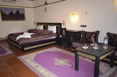 a bedroom with a bed and a table and a couch at Maison d'hôtes Ambelar in Erfoud