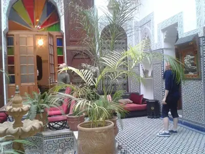 a woman walking in a room with plants in it at Ryad Naila Fes in Fès