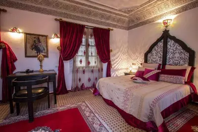 a bedroom with a bed and a desk and a window at Ryad Naila Fes in Fès