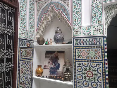 a man sitting in a shop in a room with vases at Ryad Naila Fes in Fès
