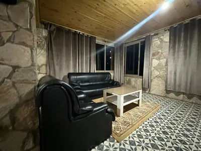 a living room with a leather couch and a table at auberge panorama ouiouane in Kasba des Aït Athmane
