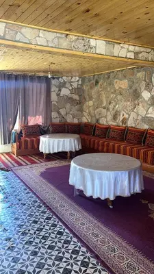 a room with couches and a table and a stone wall at auberge panorama ouiouane in Kasba des Aït Athmane