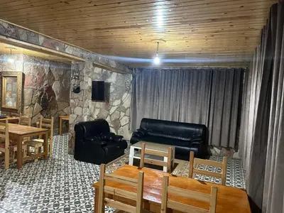 a living room with a couch and a table and chairs at auberge panorama ouiouane in Kasba des Aït Athmane