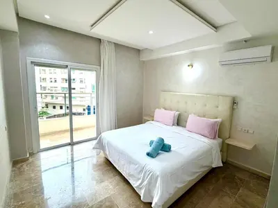 a bedroom with a white bed with pink pillows and a window at Appartement centre ville avec Wifi 200 Mo in Fès