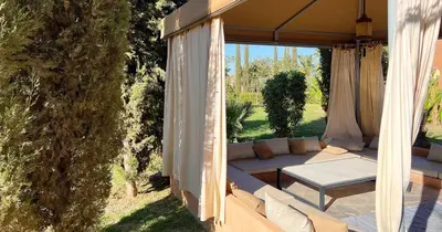 a patio with a couch and a table under an umbrella at Maison d'Hotes Oasis Marrakech Route dOuarzazate in Oulad Akkou