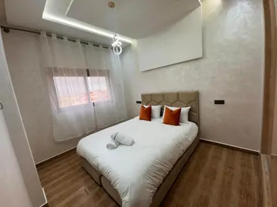 a bedroom with a large white bed with orange pillows at Appartement Calme & Moderne in Meknès