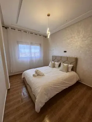 a bedroom with a large bed with white sheets and a window at Appartement Calme & Moderne in Meknès