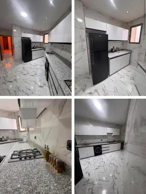 a kitchen with a black refrigerator and white counter tops at Appartement Calme & Moderne in Meknès