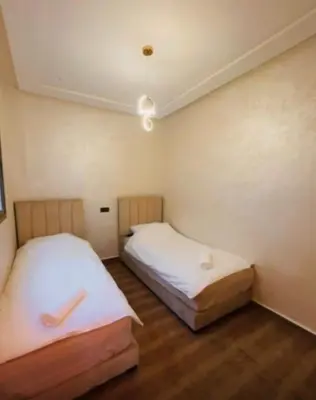 two beds in a small room with wooden floors at Appartement Calme & Moderne in Meknès