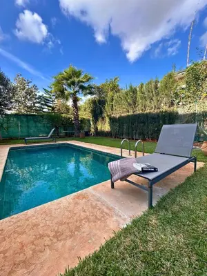 a pool with a table and a chair next to it at Elegant cocoon-private pool Bouskoura Green City in Oulad Akkou