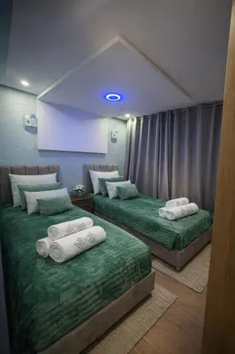 two beds in a room with green sheets and white pillows at Prime stay downtown Meknes in Meknès