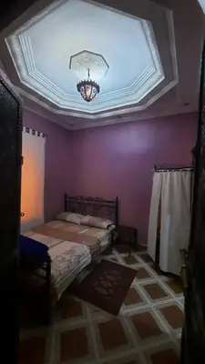 a bedroom with purple walls and a ceiling with a bed at Riad Des Artistes in Oulad Akkou