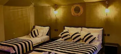 a bedroom with two beds with black and white pillows at Merzouga camping in Merzouga