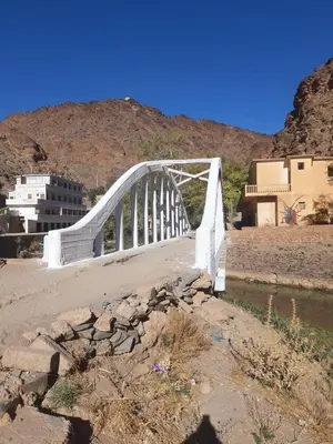 a bridge over a river with a mountain in the background at شمس ميبلادن Tafoukt N' Mibladen in Midelt