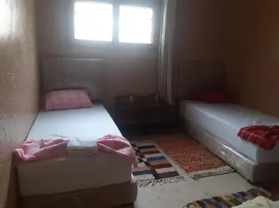 two beds in a small room with a window at شمس ميبلادن Tafoukt N' Mibladen in Midelt